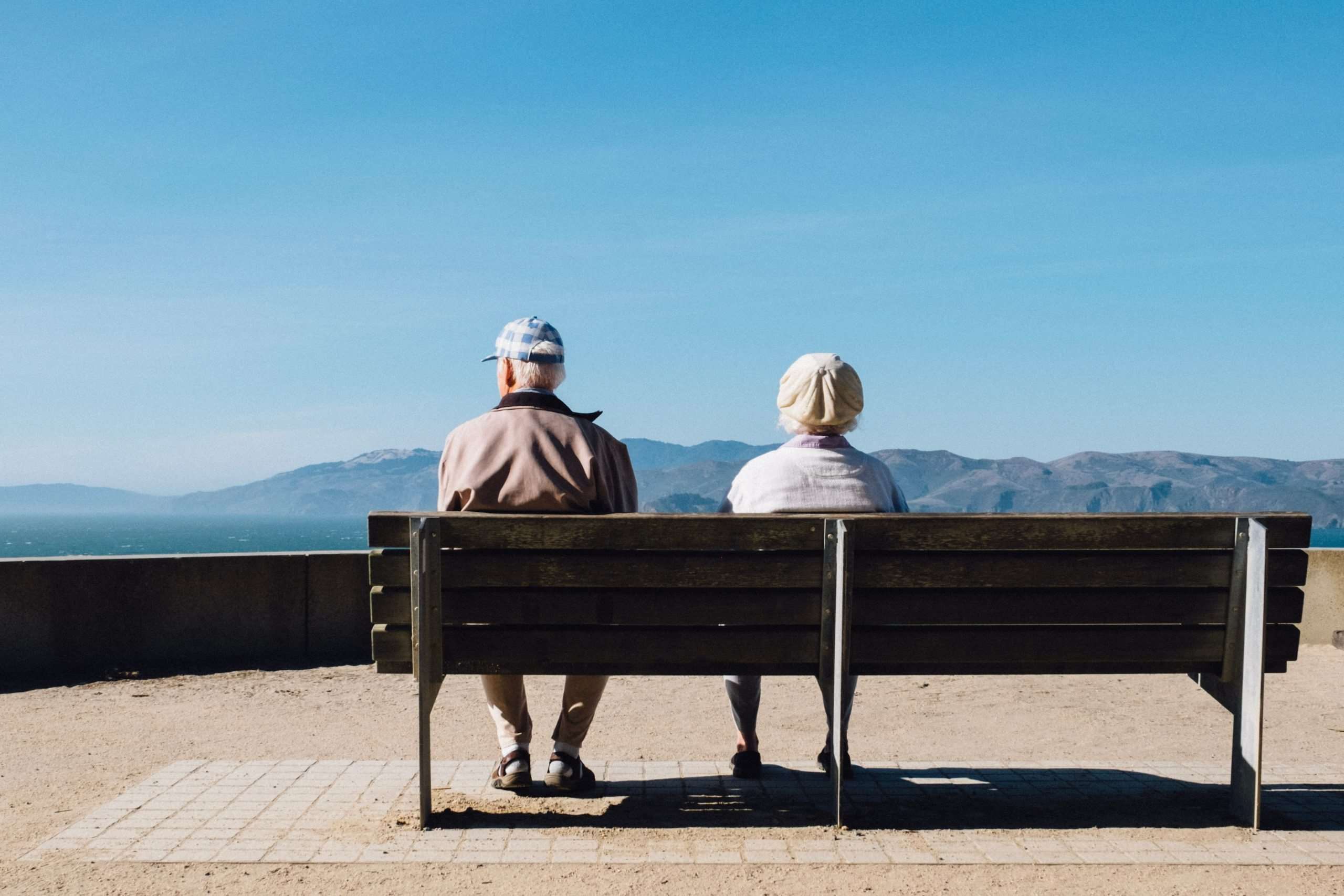 2 Rentner sitzen am Meer auf einer Bank. Für sie kann das Betreuungsrecht oder Seniorenrecht relevant werden.