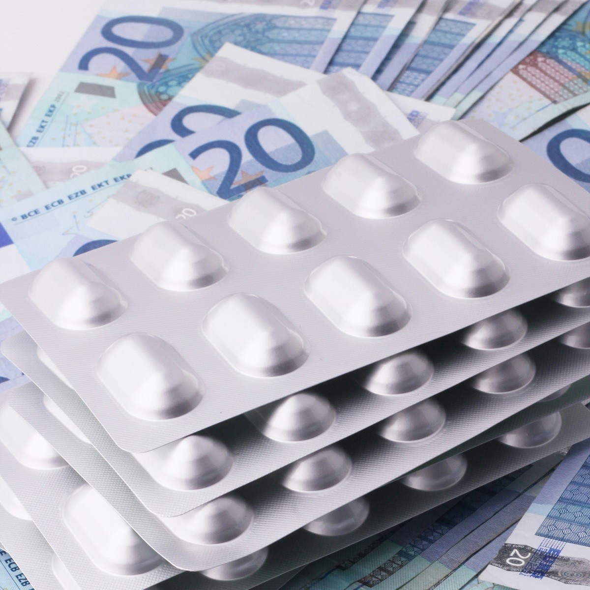 Tabletten auf Geldscheinen: Symbolbild für die Kostenübernahme der Krankenkassen.